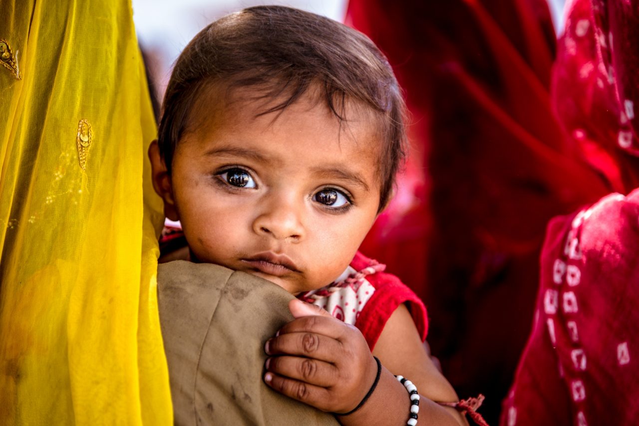 Local woman with headscarf carrying a small child in her arms, other woman in the background